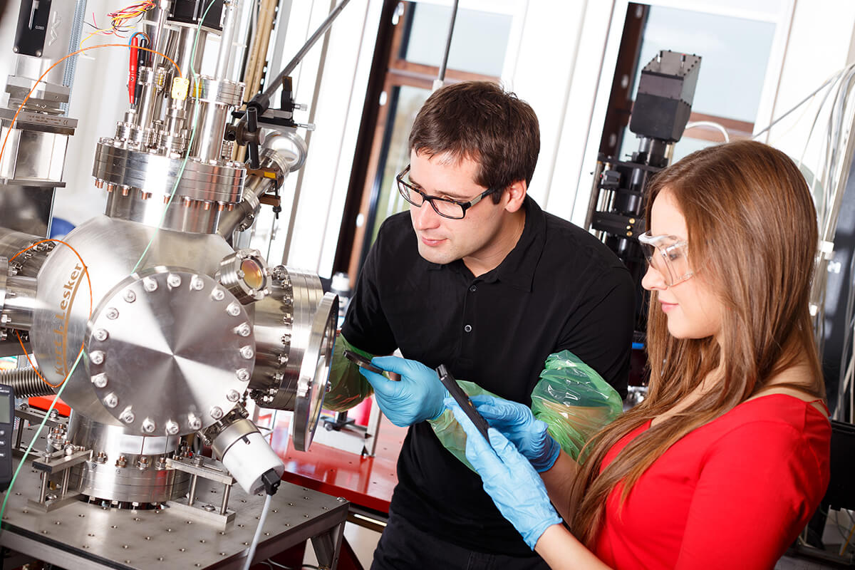 Research scientists working with laser deposits chamber technology